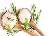 salt in spoons with fresh basil, thyme and rosemary isolated on white